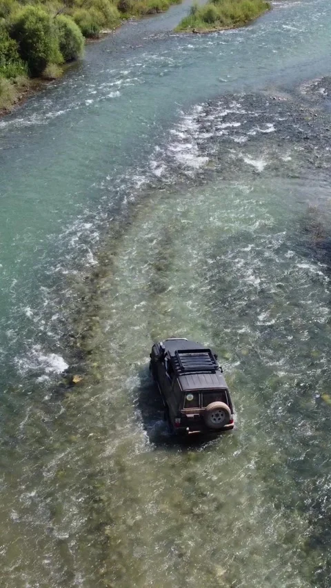 High angle rear view of black 4x4 off-road vehicle navigating through river. Stock Footage 336690881