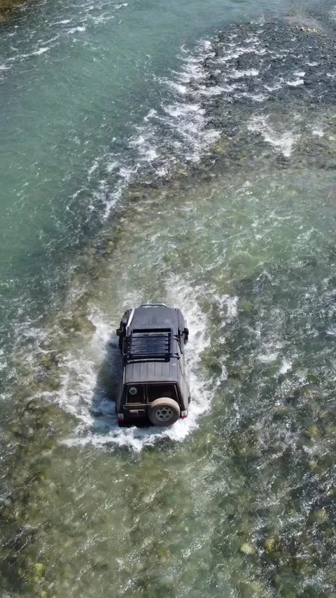 High angle rear view of black 4x4 off-road vehicle navigating through river Stock Footage 336690915