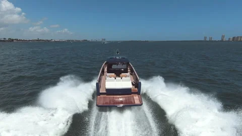 High-angle rear view of luxury motor yacht cruising fast across blue ocean Video stock 327672208