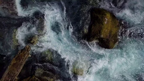 A high angle rising aerial over a fast flowing river in a forest. Stock Footage 83594862