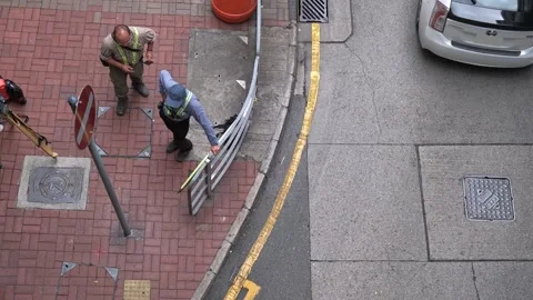 High angle shot of 2 workers chatting, corner of street, white car went by Stock Footage 254332946