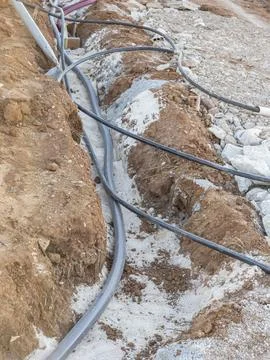 High angle shot of black plastic utility pipes and cables inside a dirt tre.. Stock Photos