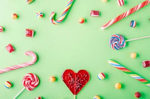 A high angle shot of candy canes and lollipops on a green background - perfec Foto stock