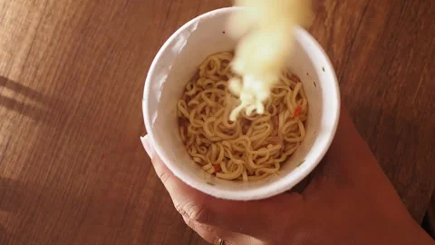 A high-angle shot captures a person's hands as they prepare instant noodles.. Stock Footage 333029766