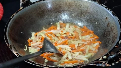 High-angle shot captures the process of stir-frying thinly sliced carrots a.. Stock Footage 330521837