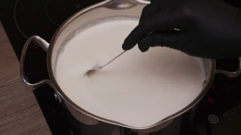 High angle shot of chef hands stirring hot milk in stainless steel pot Stock Footage 344886176