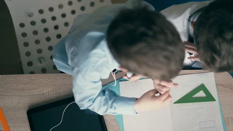 High-angle shot: Children do school homework, the elder brother, in headphones Stock Footage 105100565