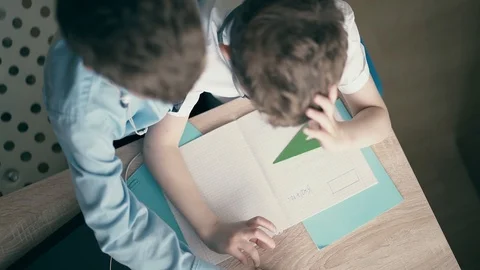 High-angle shot: Children do school homework, the elder brother, in headphones Stock-Footage 105101137