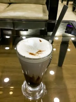 High angle shot of a cold coffee put on the table and ceiling light reflection. Foto stock