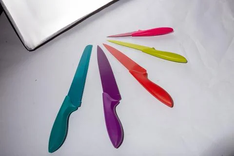 High angle shot of colorful sharp knives on a white surface under the lights Foto stock