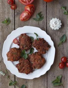A high angle shot of cutlets in a white plate on a wooden surface with mint l Stock Photos