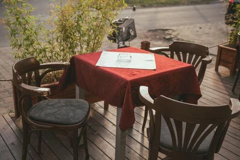 High-angle shot of an empty outdoor cafe table set with a red tablecloth, a.. Stock Photos