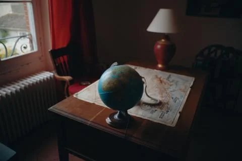 High angle shot of a globe and a map placed on a wooden table in the room Stock Photos