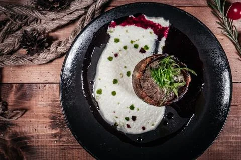 High-angle shot of a gourmet beef medallion served on a black plate with crea Stock Photos