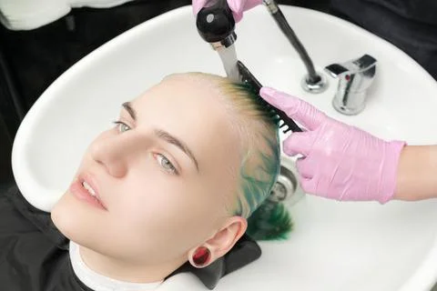 High-angle shot of head young woman in sink. Hairdresser washing green hair of Foto stock