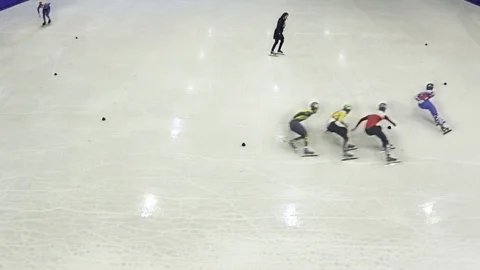 High angle shot of ice skaters skating on the rink with a referee in the middle Stock Footage 104984475