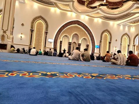 A high-angle shot inside a grand mosque shows many Muslim men praying Foto stock