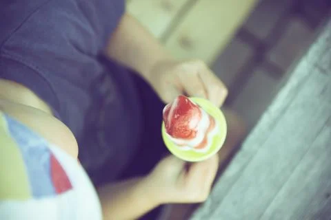 A high angle shot of a kid holding a sweet red and white lollipop with a blur Stock Photos