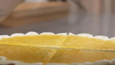 High-angle shot of a knife cutting a fresh yellow fruit tart with a wavy white c 動画素材 343019139