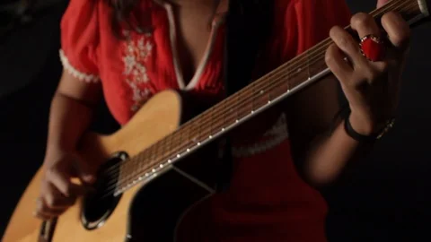 High angle shot of lady in red dress playing acoustic guitar Stock Footage 107619573