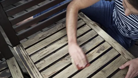 High angle shot of man sanding wooden garden chair 動画素材 114606849