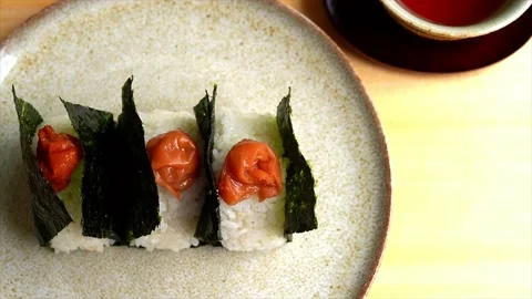 High-angle shot of Onigiri wrapped in nori with umeboshi on top Stock Footage 198040206