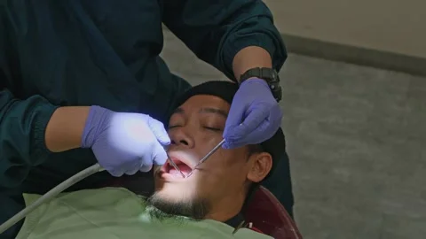 High angle shot of patient undergoing clinical oral cleaning and checkup at Видео 339758126
