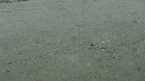 A high-angle shot of rain pouring down onto a wet concrete slab Stock Footage 340818642