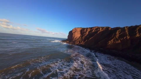 High-angle shot of reddish coastal cliffs with crashing waves Stock Footage 344582546