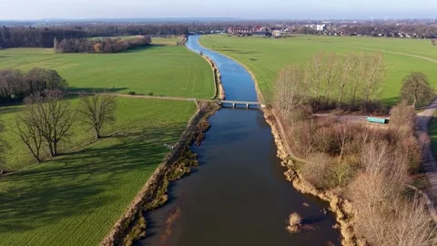 High-angle shot of a rural landscape featuring bridge crossing straight river Видео 330282429