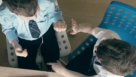 High-angle shot, Slow motion: Two boys sit on headphones, enjoy success in Video stock 105101758