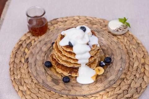 High angle shot of a stack of pancakes with cream served on a glass plate on a p Foto stock