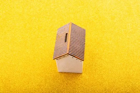 High angle shot of a tiny house figure on a yellow surface Foto stock