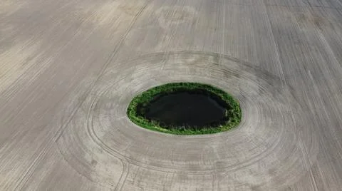 High angle shot of a tiny round lake surrounded by a thin line of greenery in a Foto stock