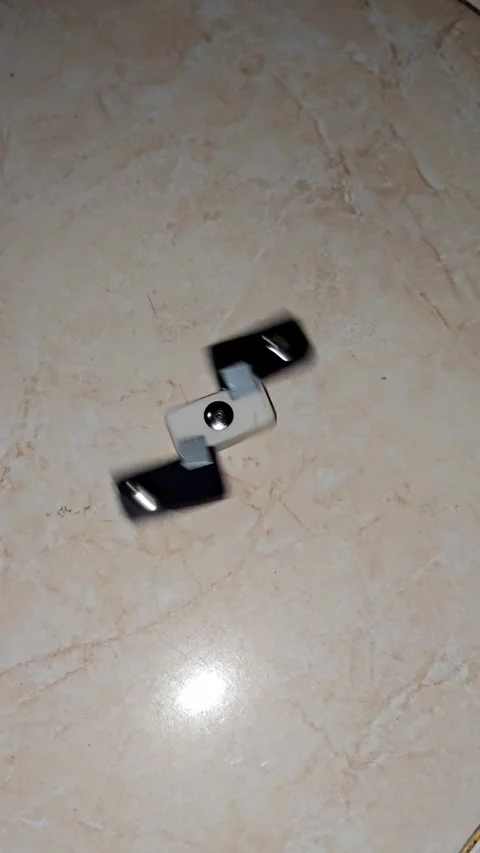 High angle shot of a two-bladed black and white fidget spinner rotating Stock Footage 336253895