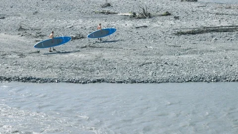 High angle shot of two paddleboarders walking away from a river Stock Footage 113256688