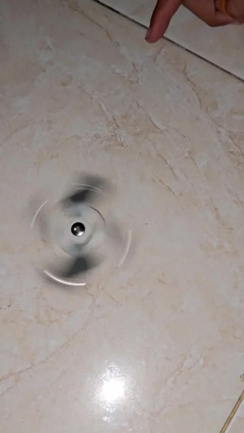 High angle shot of a white fidget spinner spinning fast on a tiled floor Video stock 336253870