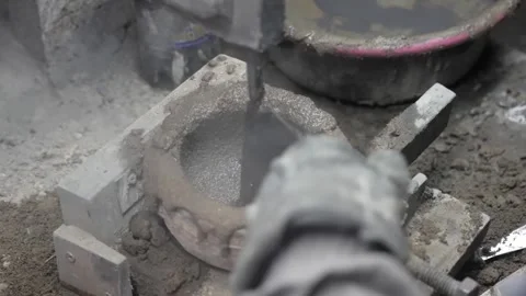 High angle shot of a worker filling a metal casting mold with wet sand and clay Stockbeeldmateriaal 332230600
