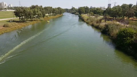 High angle shot of Yarkon River, paddle boats, buildings, park, trees, sunny day Видео 80643438