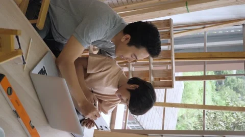 High angle, side view of Asian dad teaching his son homework in the morning Stock Footage 148833254