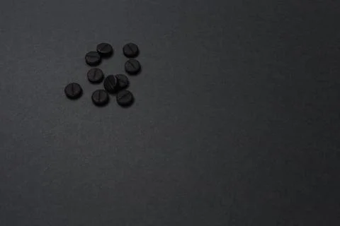 High angle side view of rough black round tablets lay on a dark grey surface Stock Photos
