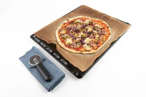 High angle studio shot of homemade pizza al tonno on black baking tray and Stock Photos