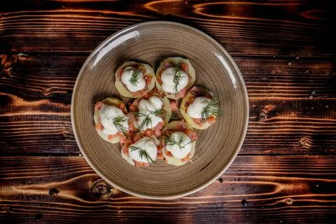 High-angle studio shot of potato rounds topped with smoked salmon, cream, and Stock Photos
