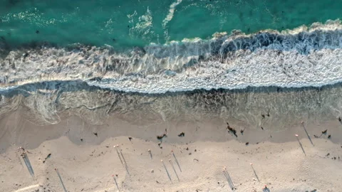 High angle top down view of blue waves crashing on a pearly white beach Stock Footage 170724347