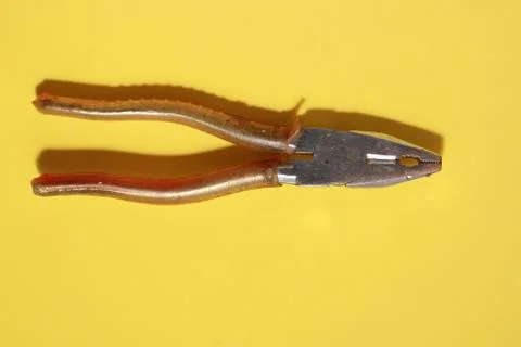 High angle top view closeup shot of pliers on a yellow table Photos