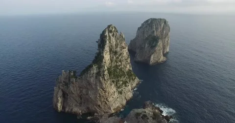 HIGH ANGLE TRACKING SHOT OF I FARAGLIONI FAMOUS ROCK FORMATIONS IN CAPRI Stock Footage 61885036