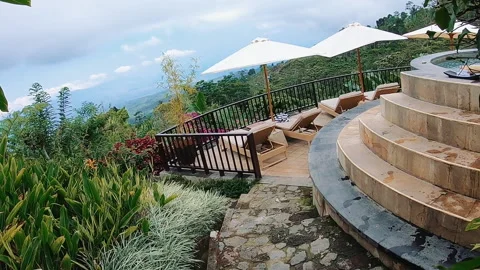 High-angle tropical terrace with circular stone spa, stepped platform, lounge Stock Footage 338443156