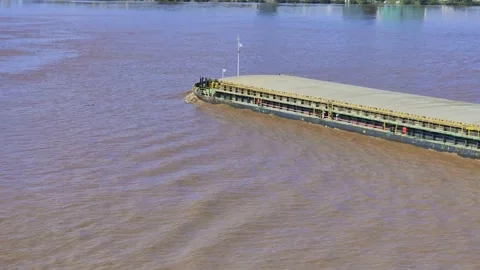High-angle video tracking a small cargo barge sailing along a wide river Video stock 347033604