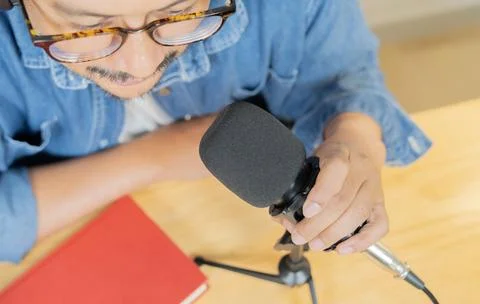 High angle view of bearded man with red book holding microphone doing podca.. Stock Photos