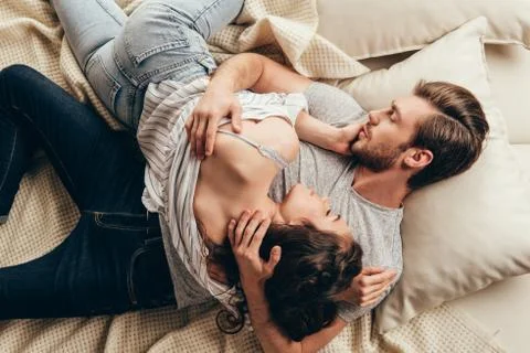 High angle view of beautiful young couple in love hugging while lying on bed Stock Photos